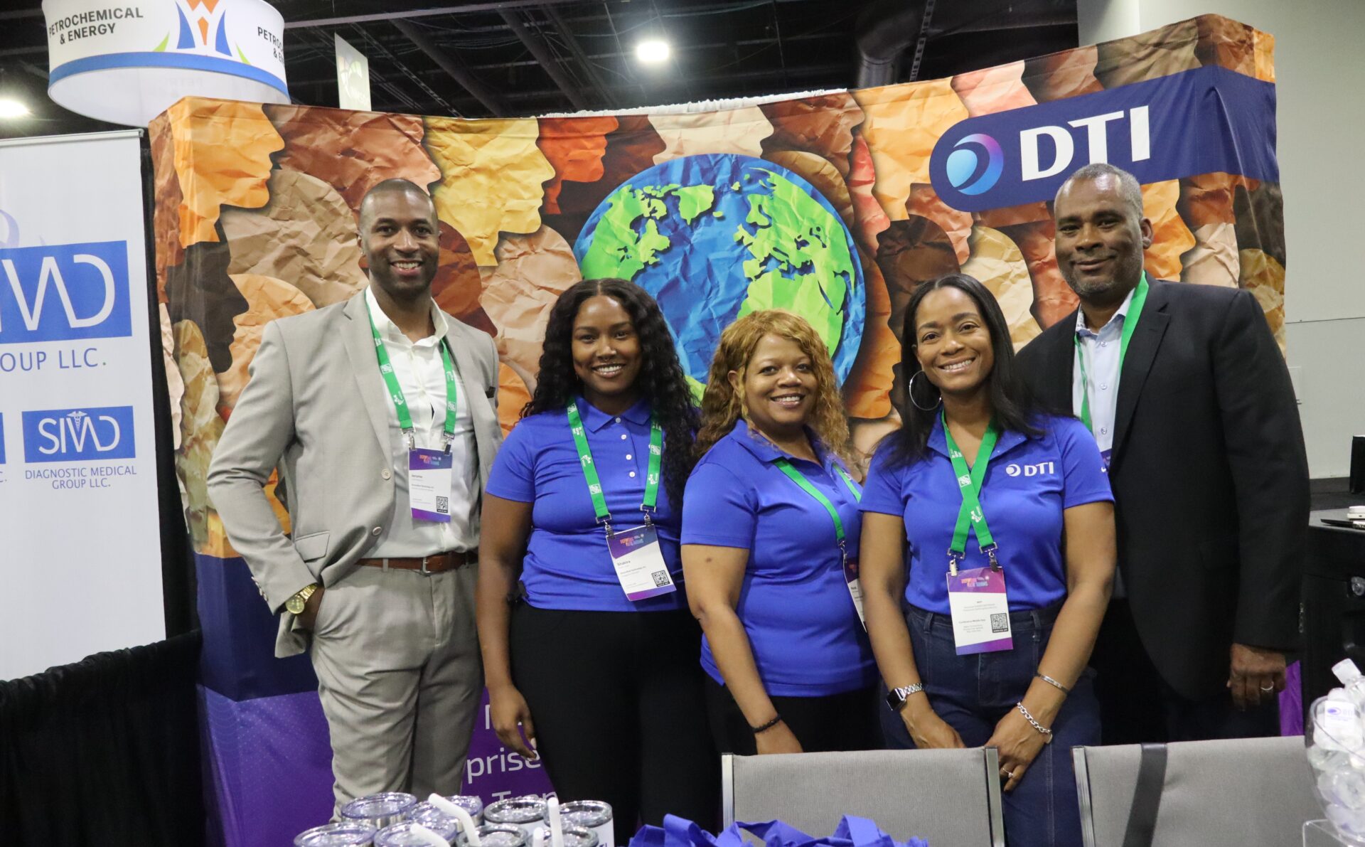 A group of diverse professionals at a conference booth smiling