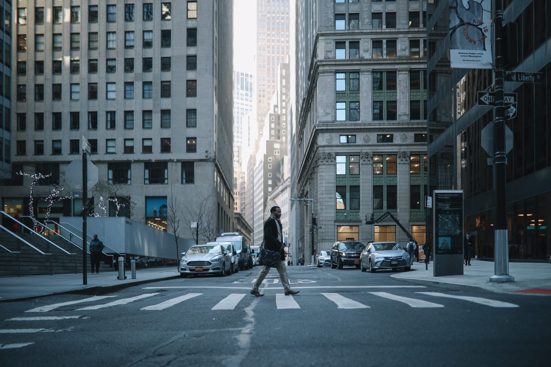 Black mid age businessman walking in NYC downtown, lower Manhattan, getting in or out to his office, wearing a coat and a suit.