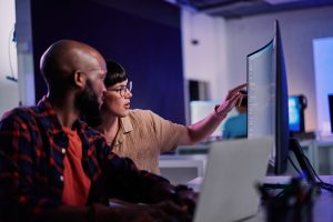 Creative developer, coding and team idea programming on computer in software or application development at office. 2 IT co-workers code on laptop or technology for testing, web design or online startup